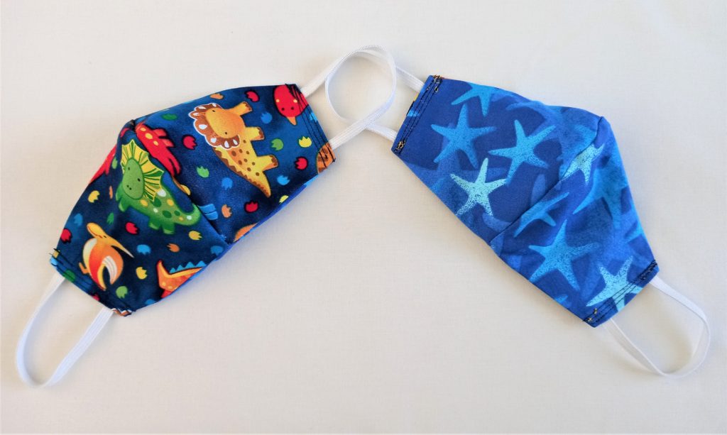 Reversible cloth face mask for kids with dinosaur and starfish patterns from Aotearoa New Zealand